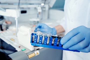 Wall Mural - bioengineer holds test tubes of blood samples for dna analysis and presence of virus in cytoplasm, b