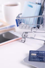 Office online paying, stay home shopping, electronic payment with credit card concept, laptop on white table background with shop cart, close up.