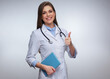Young woman doctor dressed white medical uniform holding book doing thumb up.