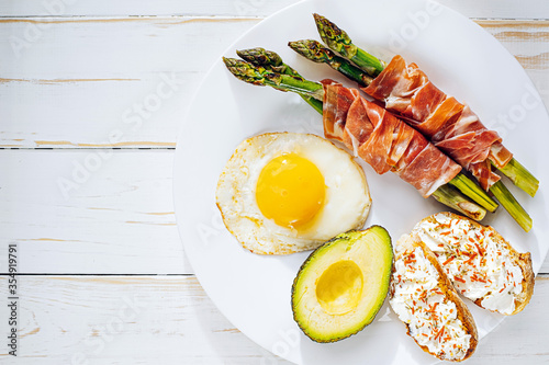 Fotografía fried asparagus wrapped in jamon, fried eggs, bruschetta with soft cheese and av