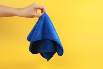 Color cleaning rag in hand on yellow background