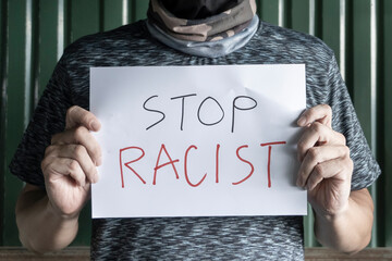 Wall Mural - A man hiding his face Holding a sign anti-discrimination message In his hand.Equality in humanity Although different nationalities concept.Stop racism, everyone should be equal in society.