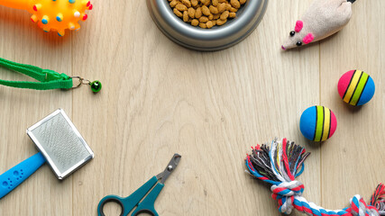 Pet care tools on wooden table top view. Flat lay composition with cat and dog accessories and bowl with dry kibble food. Veterinary shop banner mockup.