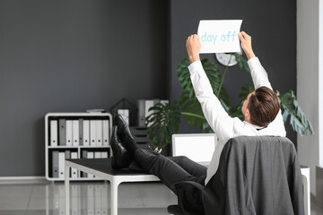 Wall Mural - Young businessman dreaming about weekends in office