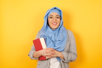 Canvas Print - Wow. Beautiful muslim woman wearing hijab isolated on bright studio background. Young emotional surprised woman standing with open mouth. Human emotions, facial expression concept. Trendy colors.