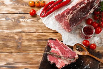 Wall Mural - Raw T-bone steak with herbs on wooden board