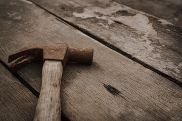 Close up of rusty hammer on old wooden texture as background,labor day,vintage style.