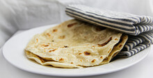 Classic homemade flour tortilla's on white plate wrapped in a cloth