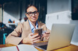 © BullRun - Clever female student writing information from online research doing homework