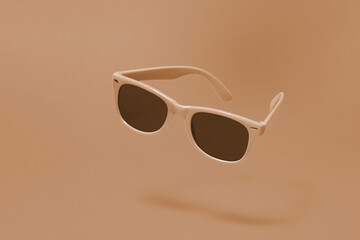 Wall Mural - Brown sunglasses floating above a matching brown background with a centre composition