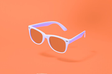 Wall Mural - Light purple sunglasses floating above an orange background with a centre composition