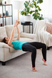 © Admiral - Fitness girl doing yoga exercise is using furniture for workout at home. Indoors training in living room. Copy space