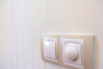 the light switch and temperature controller hang on the wall on the striped Wallpaper