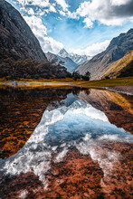 Vertical Landscape Photo Showing A Reflective Surface Lake In The Foreground And A Snowy Mountain Peak On The Background During Famous Santa Cruz Trekking In Cordillera Blanca, Peru, South America