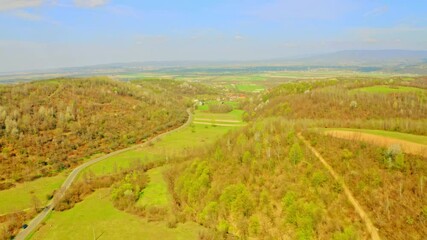 Aufkleber - drone flies above green field with young agricultural plant hills with spring trees sunny day in countryside blue sky with clouds