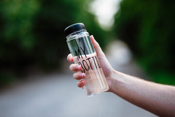 My bottle. Bottle of water in human hands. Man's hand holding a water bottle with a bottle reading 