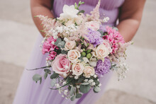close up of bridesmaid in lilac dress holding flowers