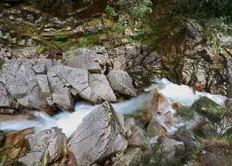 Waterfall of Mata de Albergaria in the middle of the woods the water runs down the rocks until de green lake