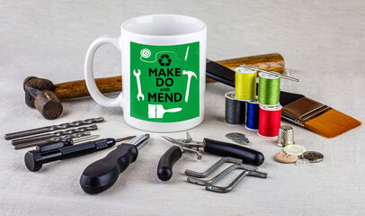 Wall Mural - Make do and mend logo on coffee mug surrounded by tools on table cloth, homespun movement for sustainable living and to reduce waste.