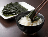 Fototapeta  - Wrapping nori around rice set against a wooden backdrop.