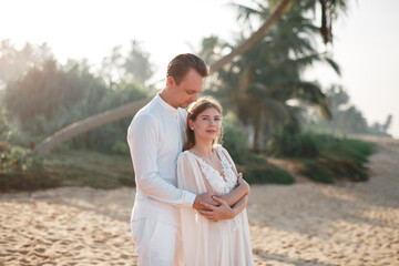 Wall Mural - Happy just married young wedding couple celebrating and have fun at beautiful beach sunset. Attractive young bride and groom hugging on the beach. Wedding couple. Just married