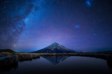 night sky over mt. taranaki reflecting in pouakai pool, new zealand