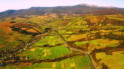 Poster - aerial view on village in valley hills with trees road with driving car mountains landscape spring season in daytime