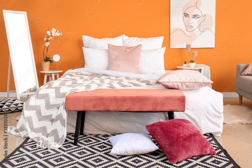 Stylish interior of room with big bed and bench