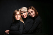 Family Close-up Portrait. Mom And Two Daughters Are Hugging And Looking At The Camera.