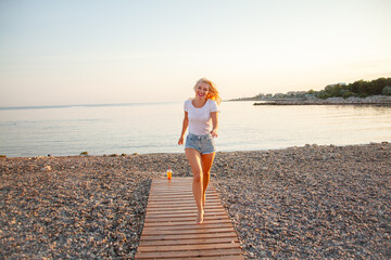 Hot blond woman running on the uninhabited beach. the lifestyle of people are the happiness vacation. Girl dressed jeans  short and t-shirt.