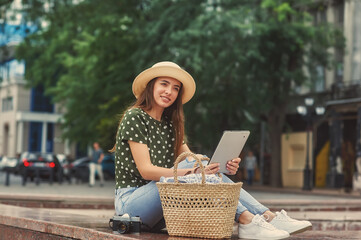 Young beautiful woman with a digital tablet in a city Park. Smiling tourist girl resting in the open air.