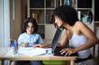 © AUFORT Jérome - metis woman working home with her son doing his homework
