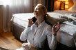 © JustLife - Young businesswoman talking to the phone in hotel. Beautiful woman working in hotel room.