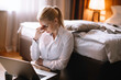 © JustLife - Tired businesswoman working on lap top. Beautiful woman working in hotel room.