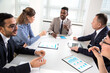 © chagin - International group of business people working and communicating sitting near office desk.