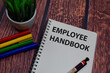 Book about Employee Handbook isolated on wooden table.