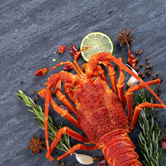 Cooked boiled lobster, delicious dinner seafood meal set with knife and fork on black stone slate background, restaurant menu design, top view, overhead