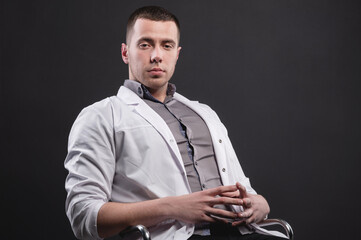 Portrait of a young intern doctor. A man is standing in a photo studio. Making a diagnosis. Studio portrait