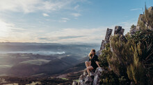 Aerial Shot - Beautiful Asian Woman Sit And Posing At The Top Of The Organ Pipes , Mt Cargill Dunedin New Zealand.