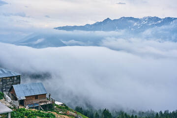 landscape photo of wooden houses and foggy mountains. fog starts covering gito plateau, rize, black 