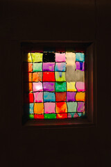 Square, multi-colored, old, hand made stained glass window. A small window with a stained glass window.