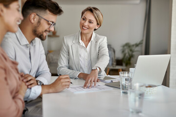 Canvas Print - Happy insurance agent talking to a couple and offering them a contract to sign.