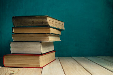 Poster - Old books on a old wooden table. Beautiful green wall background.