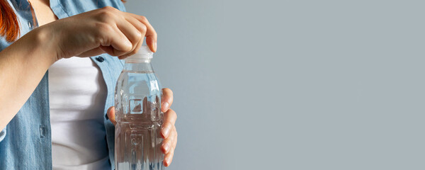 Woman hand opening water bottle in room with copyspace. Thirst Concept