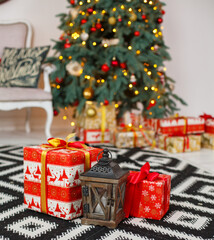 Christmas presents/gifts under fir-tree. Vintage New Year decorations. Red gift boxes and lantern under fir-tree. Christmas mood. Celebrating of New Year