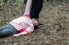 A Man Drags The Body Of A Teenage Girl On The Ground In The Woods. Victim Of Violence. The Concept Of Child Abduction And Abuse.