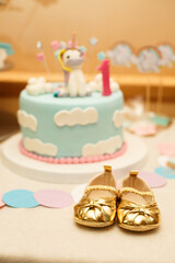 Wall Mural - little golden girl's booties on background of birthday cake. first birthday party. little lady
