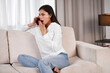 © Антон Пухов - Young woman. Beautiful healthy girl is talking on the video calling phone. Model is sitting on the sofa at home. Portable Electronics At Home