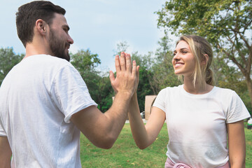 Wall Mural - Young couple smile and greet with hi-five when first meet in the park