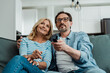 © LIGHTFIELD STUDIOS - Selective focus of smiling mature couple watching tv on sofa
